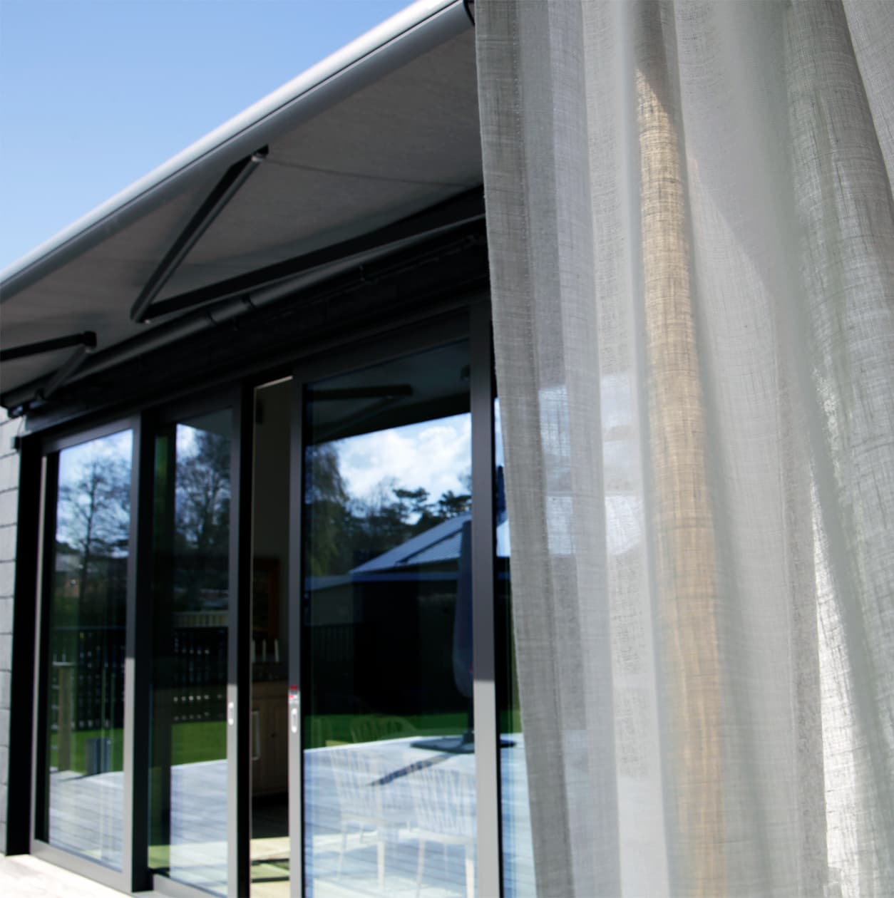 Terrassmarkis markis gardin ute Terrassmarkis grå snett underifrån perspektiv inifrån ljus gardin i förgrunden