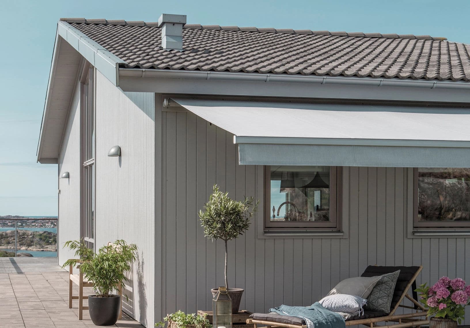 Skugga altan uteplats markis solskydd Husknut ljust trähus markis över terrass fasad skuggar uteplats